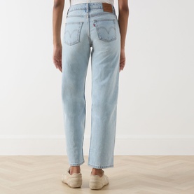 Model wearing Levi's straight leg jeans in light blue denim, rear view, styled with cream trainers