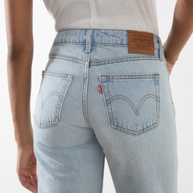 Model wearing Levi's straight jeans in light blue wash, close-up of rear view showing back pockets, red tab logo and leather patch detail