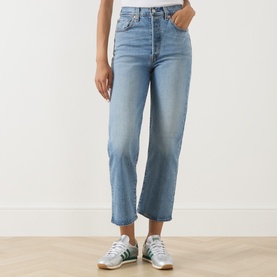Model wearing light blue straight-leg cropped jeans with high waist, styled with green and white trainers