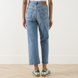 Model wearing light blue straight-leg cropped jeans, rear view, styled with white and green trainers