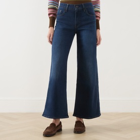Model wearing Levi's True Blue Dark wide leg jeans, styled with a striped knit and brown loafers