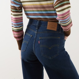 Model wearing Levi's True Blue Dark wide leg jeans, rear view, styled with a multicoloured striped top.