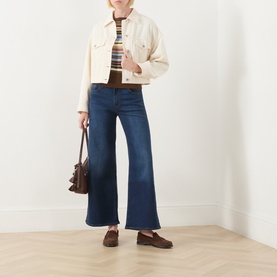 Model wearing Levi's True Blue Dark wide leg jeans with cream denim jacket, striped top, brown loafers, carrying brown leather bag