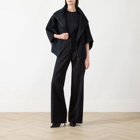 Model wearing Max Mara Main ultramarine cashmere cape coat with contrast trim, styled with black wide-leg trousers and heels.