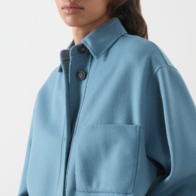 Model wearing Max Mara Weekend light blue wool coat, close-up showing collar, button placket and chest patch pocket detail.