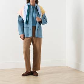 Model wearing Max Mara Weekend light blue wool coat with colourblock scarf, styled with tan trousers and brown loafers.