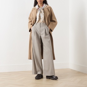 Model wearing Max Mara Weekend camel wool coat, styled with wide-leg grey trousers, striped blouse, printed scarf and black loafers.
