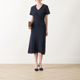 Model wearing Max Mara Main ultramarine V-neck short-sleeve midi dress with fitted waist, styled with navy flats and a brown clutch.