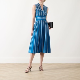 Model wearing Max Mara Main Agreste Stripe Dress in Ocean, sleeveless V-neck midi with flared skirt. Styled with black heels and clutch.