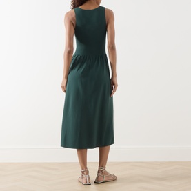Model wearing Max Mara Weekend Calibri Flared Dress in green, sleeveless midi length, styled with strappy flat sandals, rear view.