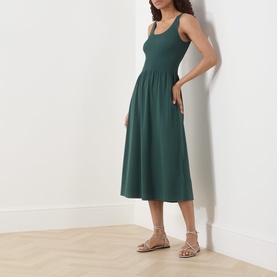 Model wearing Max Mara Weekend Calibri Flared Dress in green, ribbed upper, midi length, with gold strappy flat sandals