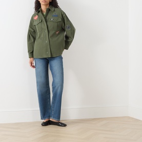 Model wearing Max Mara Weekend khaki cotton jacket with embroidered patches, styled with blue straight-leg jeans and black flat shoes.