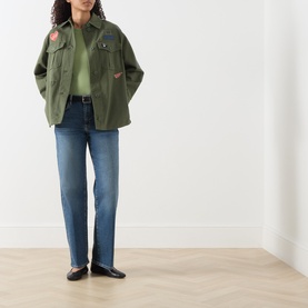 Model wearing Max Mara Weekend khaki cotton jacket with embroidered patches, styled with blue straight-leg jeans and black flat shoes.