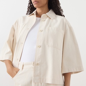 Model wearing Max Mara Weekend ecru cotton cropped jacket with short sleeves and chest pocket, styled with white top and ecru trousers