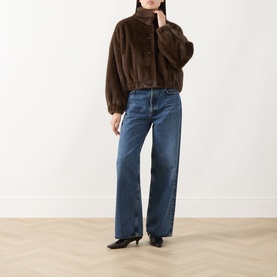 Model wearing Max Mara Weekend Anemone Faux Fur Jacket in brown with stand collar, styled with wide-leg blue jeans and black kitten heel shoes.