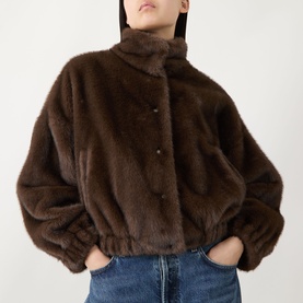 Model wearing Max Mara Weekend Anemone Faux Fur Jacket in brown, with stand collar, press-stud front and elasticated hem, styled with blue jeans.