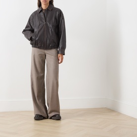 Model wearing Max Mara Weekend dark brown leather jacket with zip fastening, styled with wide-leg taupe trousers and black shoes.