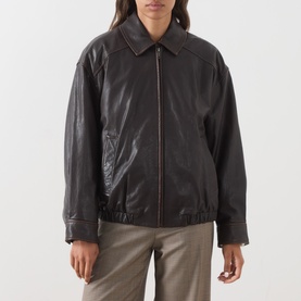 Model wearing Max Mara Weekend dark brown leather jacket with zip front, collar, and elasticated hem, styled with taupe trousers.