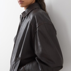 Model wearing Max Mara Weekend dark brown leather jacket, shown in close-up detail highlighting collar and oversized silhouette.