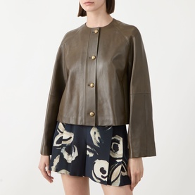 Model wearing Max Mara Main Bouquet Cropped Leather Jacket in khaki, collarless with gold buttons, styled with a floral print mini skirt.