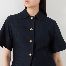 Model wearing Max Mara Main ultramarine cotton jacket with short sleeves, pointed collar, and gold button fastening.