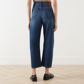Model wearing dark blue wide-leg cropped jeans, rear view, styled with black loafers on light wood floor