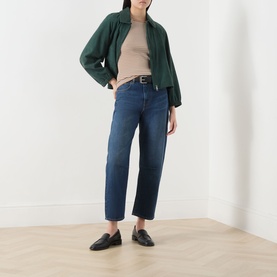 Model wearing dark blue cropped straight-leg jeans with a green jacket, beige top, black belt, and black loafers
