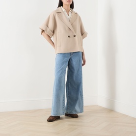 Model wearing Max Mara Weekend Zattera Wide Leg Jeans in blue, styled with a beige double-breasted wool coat and brown loafers.