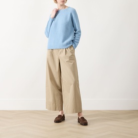 Model wearing Max Mara Weekend Ghiacci Light Blue knitted sweater with crew neck, styled with wide-leg beige trousers and brown loafers