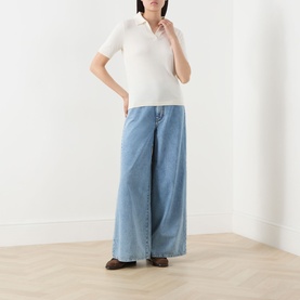 Model wearing Max Mara Weekend Roncolo Knit Polo Shirt in ecru with wide-leg light blue denim jeans and brown loafers.