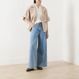 Model wearing Max Mara Weekend Roncolo Knit Polo Shirt in ecru with wide-leg light blue jeans and brown loafers