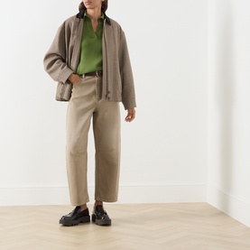 Model wearing Max Mara Weekend Albero Open Collar Knitted Polo Shirt in green, styled with taupe jacket, beige wide-leg trousers and black loafers.