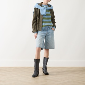 Model wearing Max Mara Weekend Ghiacci Stripe Sweater in olive and blue stripes, styled with denim shorts, khaki jacket, and grey boots.