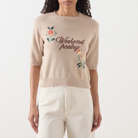 Model wearing Max Mara Weekend sand knit top with Weekend Poetry embroidery and floral detail, short sleeves, styled with white trousers.