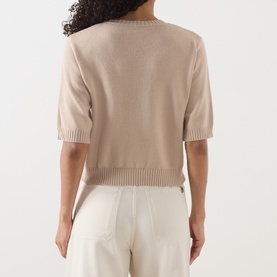 Model wearing Max Mara Weekend Sand Writing cotton knit top, short sleeves, ribbed hem, back view, styled with cream trousers.