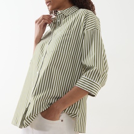 Model wearing Max Mara Weekend Giralda Striped Shirt in green, with shirt collar, cropped sleeves and structured cuffs, styled with white trousers.