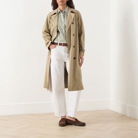 Model wearing Max Mara Weekend Giralda Striped Shirt in Green Fine, styled with a beige trench coat, white trousers and brown loafers.
