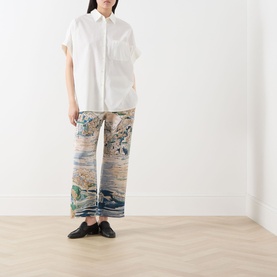 Model wearing Max Mara Weekend white cotton and silk shirt with short sleeves, styled with multicolour printed trousers and black loafers.