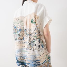 Model wearing Max Mara Weekend white cotton and silk shirt, rear view showing scenic coastal landscape print across back panel, short sleeves