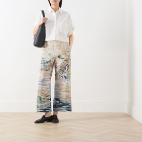 Model wearing Max Mara Weekend white cotton and silk shirt, styled with printed wide-leg trousers and black loafers, carrying black tote bag.