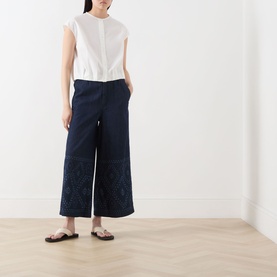 Model wearing Max Mara Weekend Gelatina Cropped Blouse in white, collarless with cap sleeves, styled with navy wide-leg cropped trousers and sandals.
