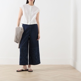 Model wearing Max Mara Weekend Gelatina Cropped Blouse in white with navy wide-leg trousers and flat sandals, carrying a grey woven bag.