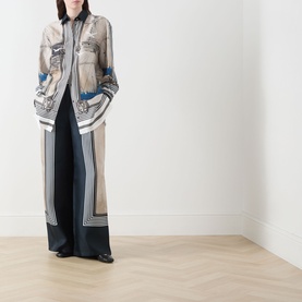 Model wearing Max Mara Main Teglia Printed Shirt in Stone Boats silk with boat-themed print, styled with wide-leg dark trousers and black shoes.