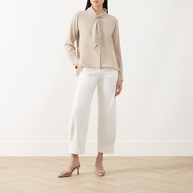 Model wearing Max Mara Dry Bow-Neck Silk Blouse in stone with white wide-leg trousers and nude heels.