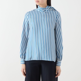 Model wearing Max Mara Main silk pinstripe high-neck blouse in blue and navy, with navy tailored trousers visible below.