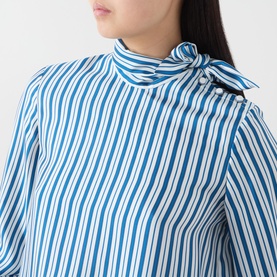 Model wearing Max Mara Main silk pinstripe shirt in blue and white, featuring a tie neck and button shoulder detail
