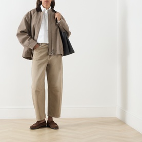 Model wearing Max Mara Weekend Ariano Lace Cut-Out Blouse in White Lace, styled with taupe trousers, brown jacket and loafers.