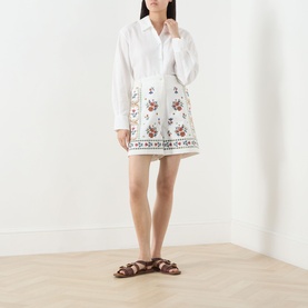 Model wearing Max Mara Weekend Obice Embroidered Shorts in White Cross with floral embroidery, styled with a white shirt and brown sandals.