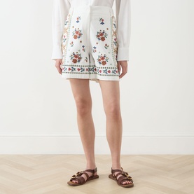 Model wearing Max Mara Weekend Obice Embroidered Shorts in White Cross with floral embroidery, styled with a white shirt and tan sandals.