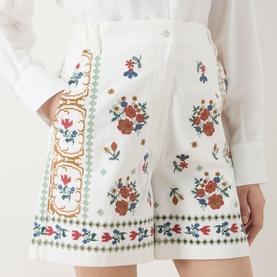 Model wearing Max Mara Weekend Obice Embroidered Shorts in White Cross with multicolour floral embroidery, styled with a white shirt.